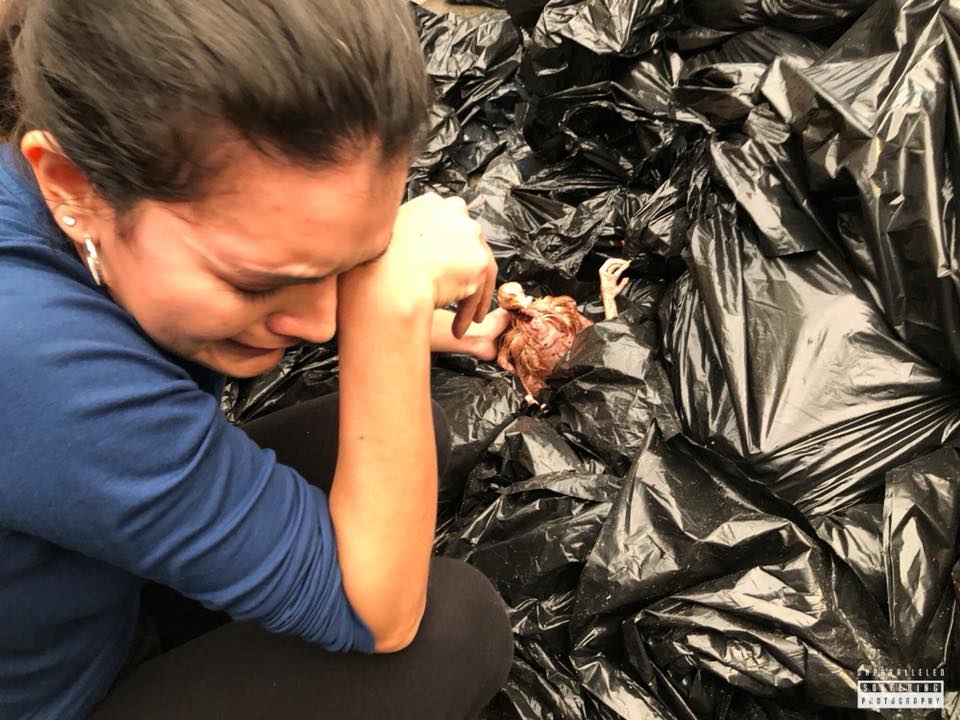 Crying woman reaching for a chicken in the garbage